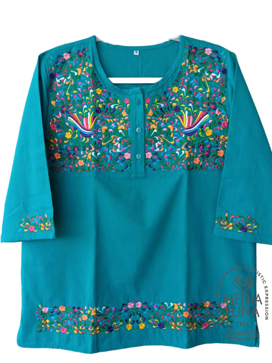 Blusa color turquesa con bordado de colibríes y motivos florales.